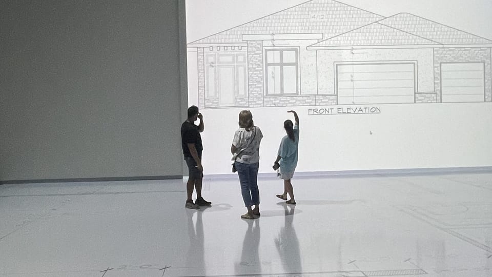 Clients walking a floor plan projected at full scale on the Walk Your Plans studio floor